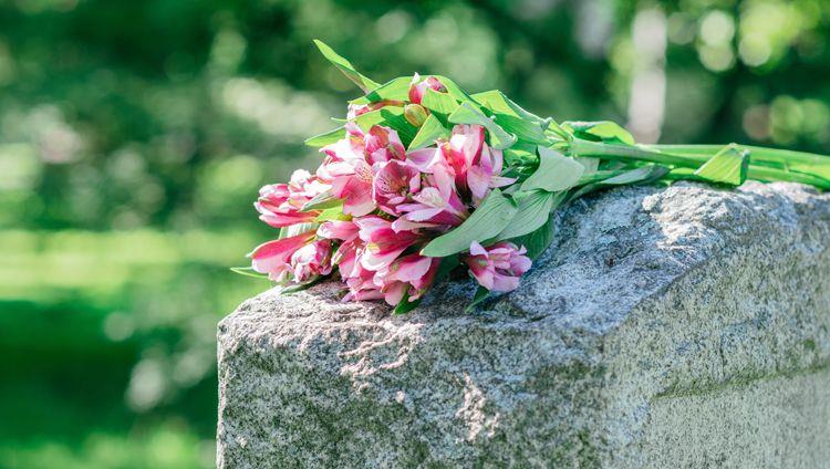 Red lilies resting on top of a granite monument